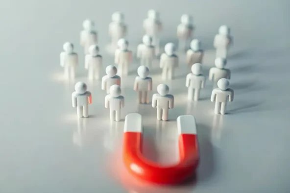 Roter Magnet zieht kleine Figuren an – Symbol für Wahlkampfstrategien und Wählergewinnung bei der Betriebsratswahl.